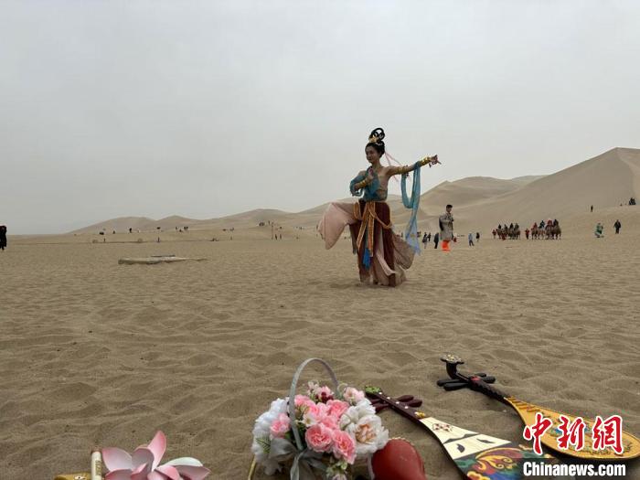 圖為2023年4月底，敦煌大漠“逐舞者”奧楠在鳴沙山月牙泉景區(qū)視頻直播敦煌舞。　馮志軍 攝