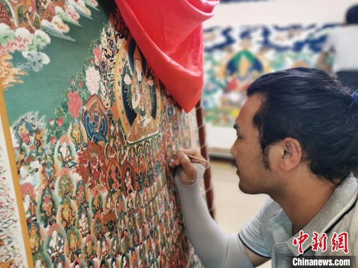 圖為更登才讓的徒弟繪畫唐卡?！?zhí)砀?攝