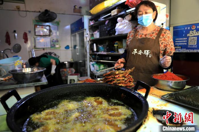 圖為平安驛·河湟民俗文化體驗地內的商戶炸干板魚。　薛蒂 攝