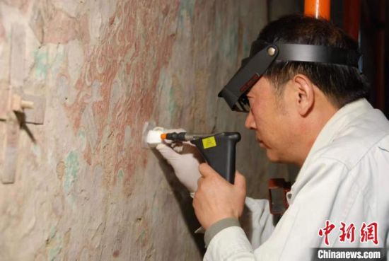 敦煌研究院研究員樊再軒進(jìn)行壁畫修復(fù)。(資料圖)張?jiān)莆?攝